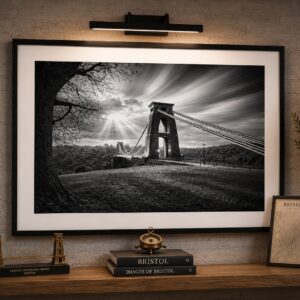 Framed black and white Clifton Suspension Bridge wall art print featuring dramatic sun rays and sweeping clouds over Avon Gorge.