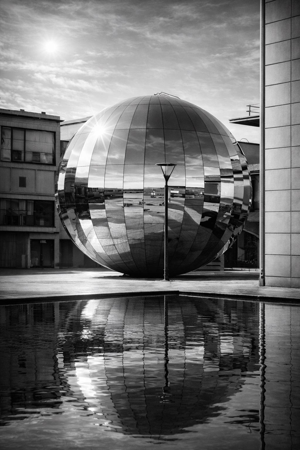 Black and white photograph of a reflective sphere in Bristol with water reflections